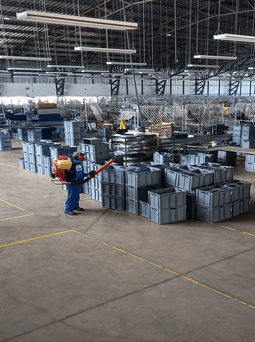 Técnico aplicando control de plagas en bodega industrial