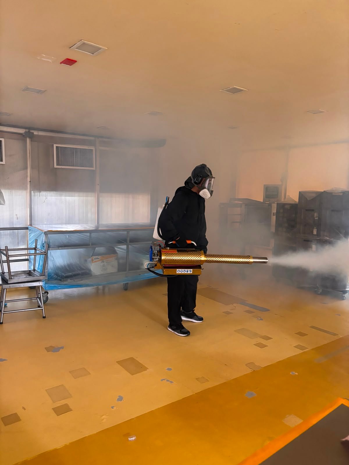 Técnico realizando termonebulización en planta industrial
